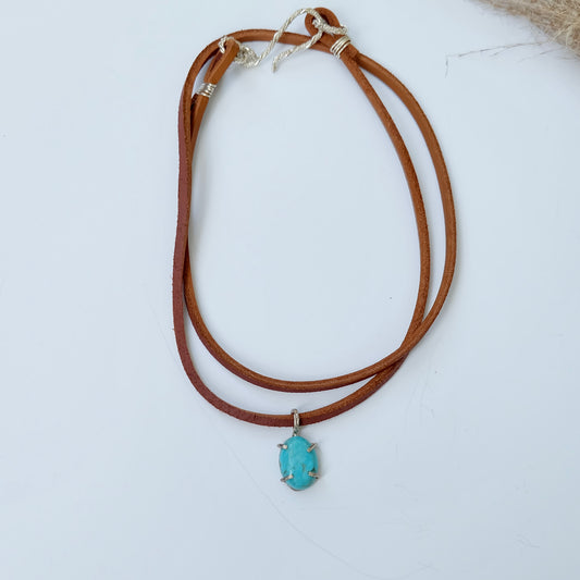 Turquoise charm necklace with brown leather strap.