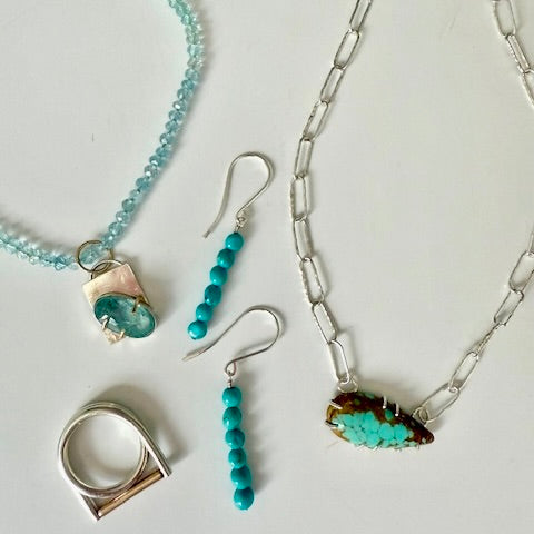 Turquoise dangle earrings displayed with other sterling silver pieces