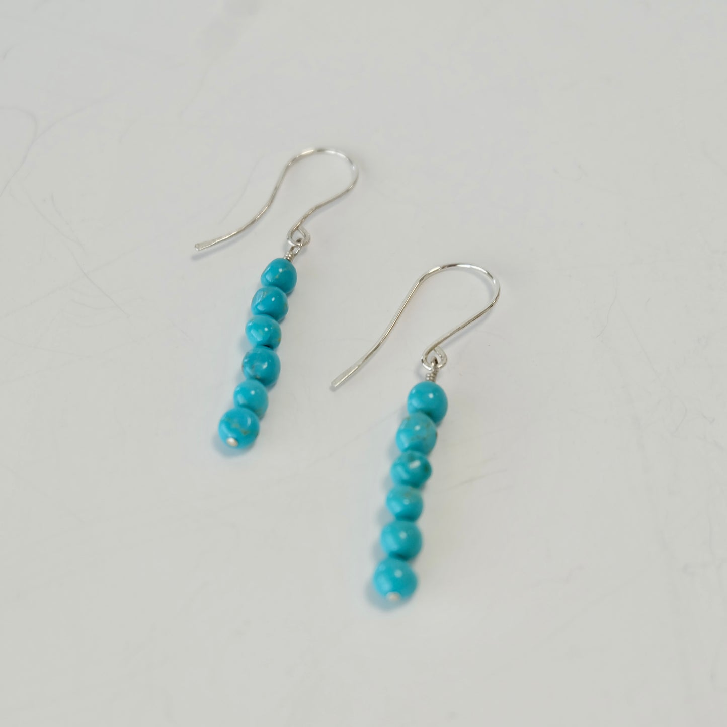 Turquoise sterling silver dangle earrings displayed on background