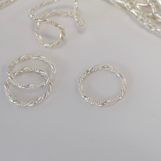 A detailed image of a twisted ring, emphasizing its unique design with a spiraling form and smooth surface.