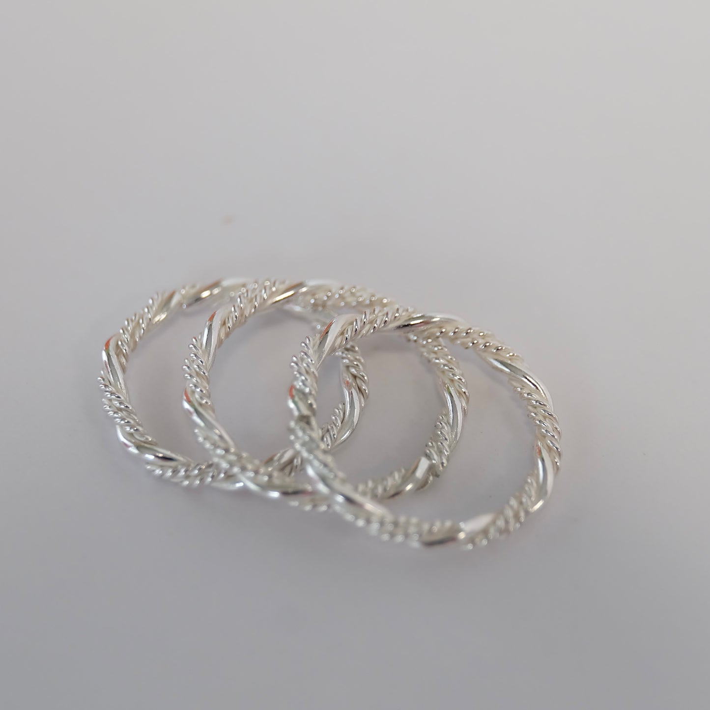 A close-up view of a twisted ring, showcasing its intricate design and unique spiral shape in a polished finish.