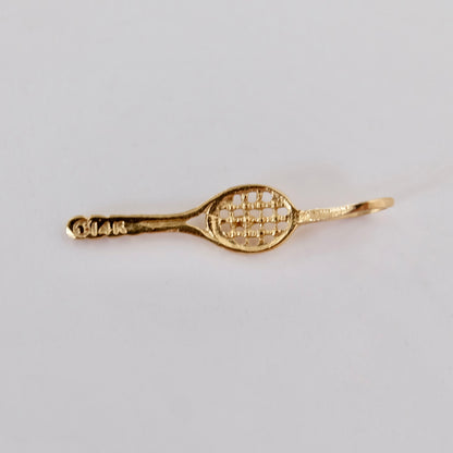 Close-up of a vintage 14K gold tennis racket charm showing the strings and handle