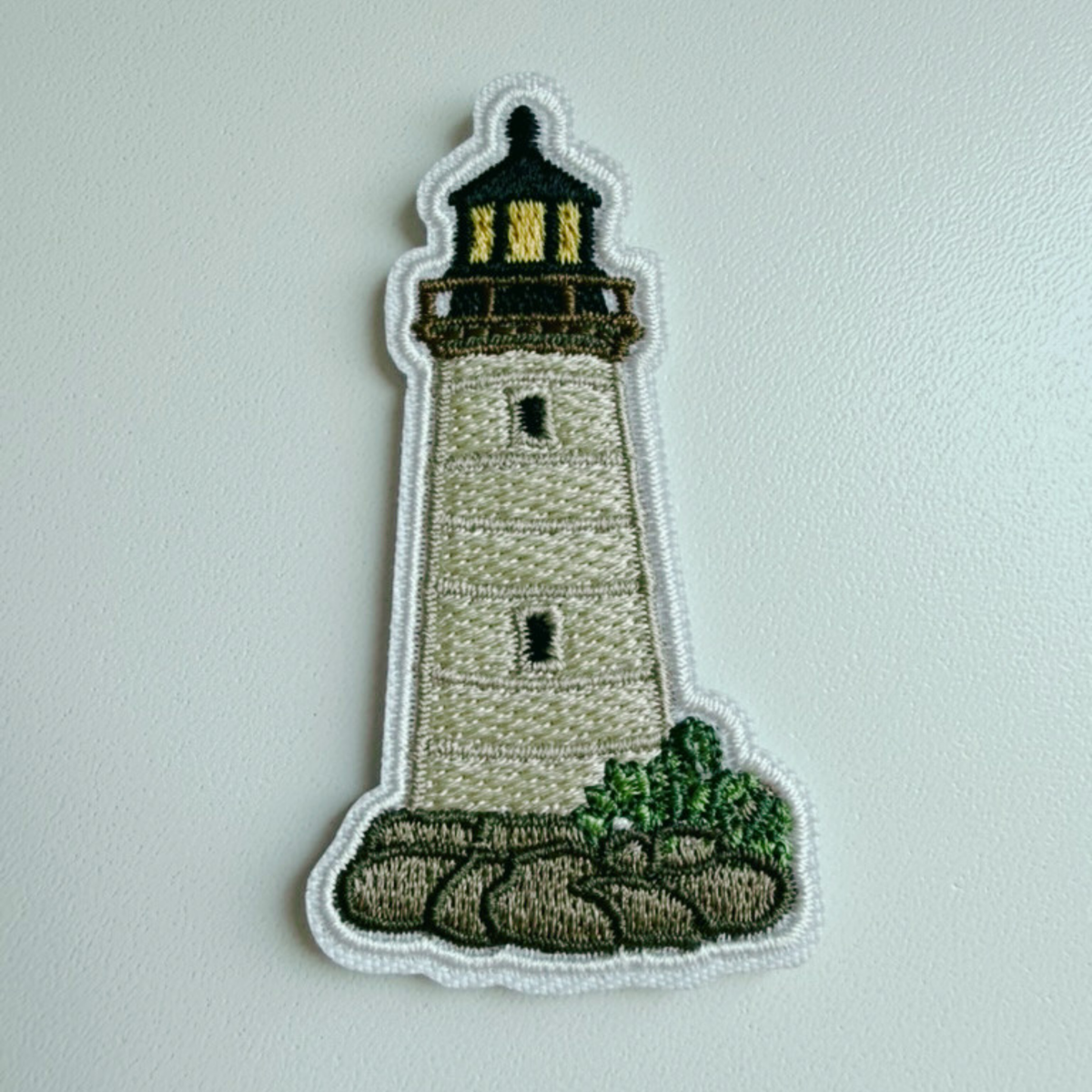 Vintage lighthouse iron-on patch with rocky shore