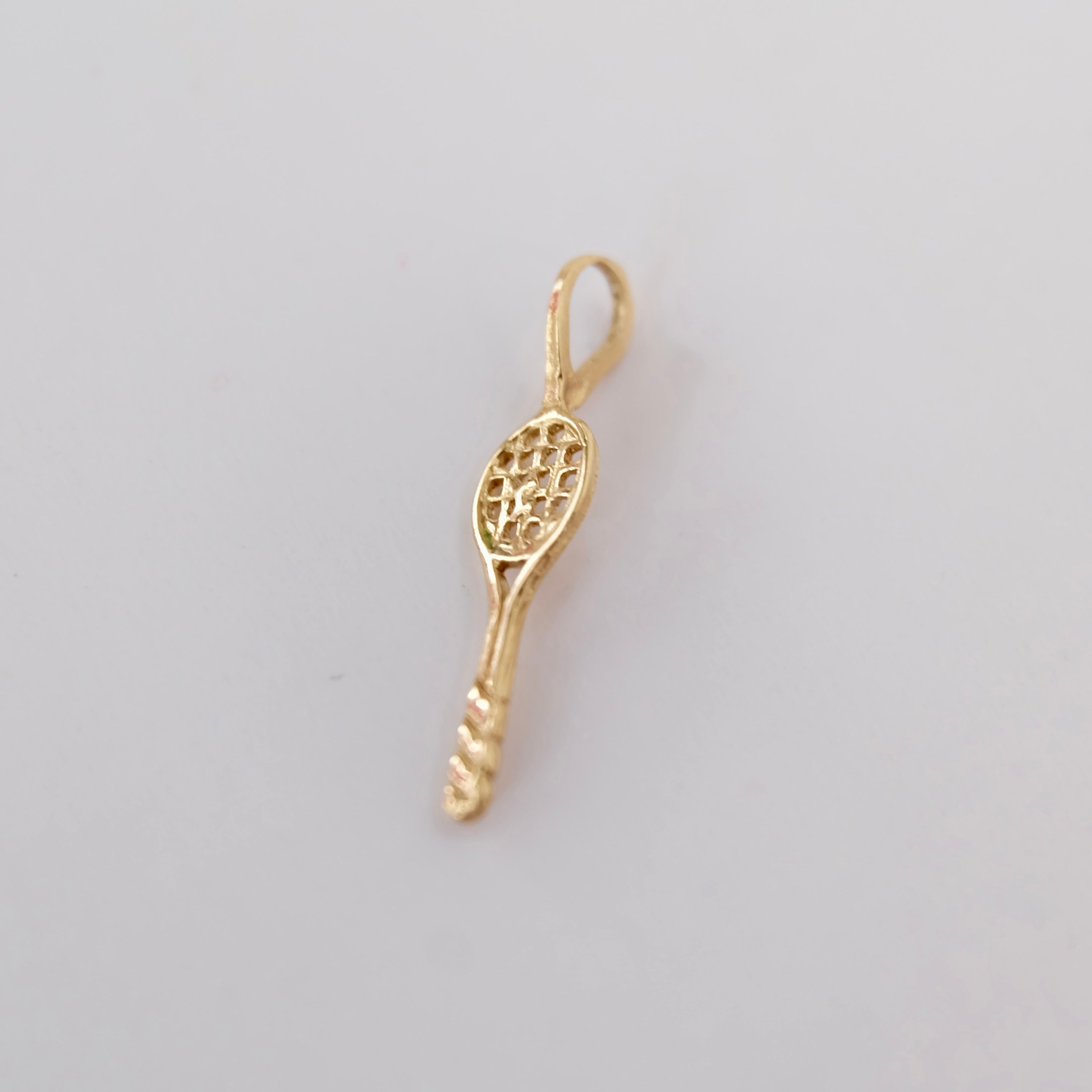 A vintage tennis racquet charm featuring 14k gold displayed on white background. 