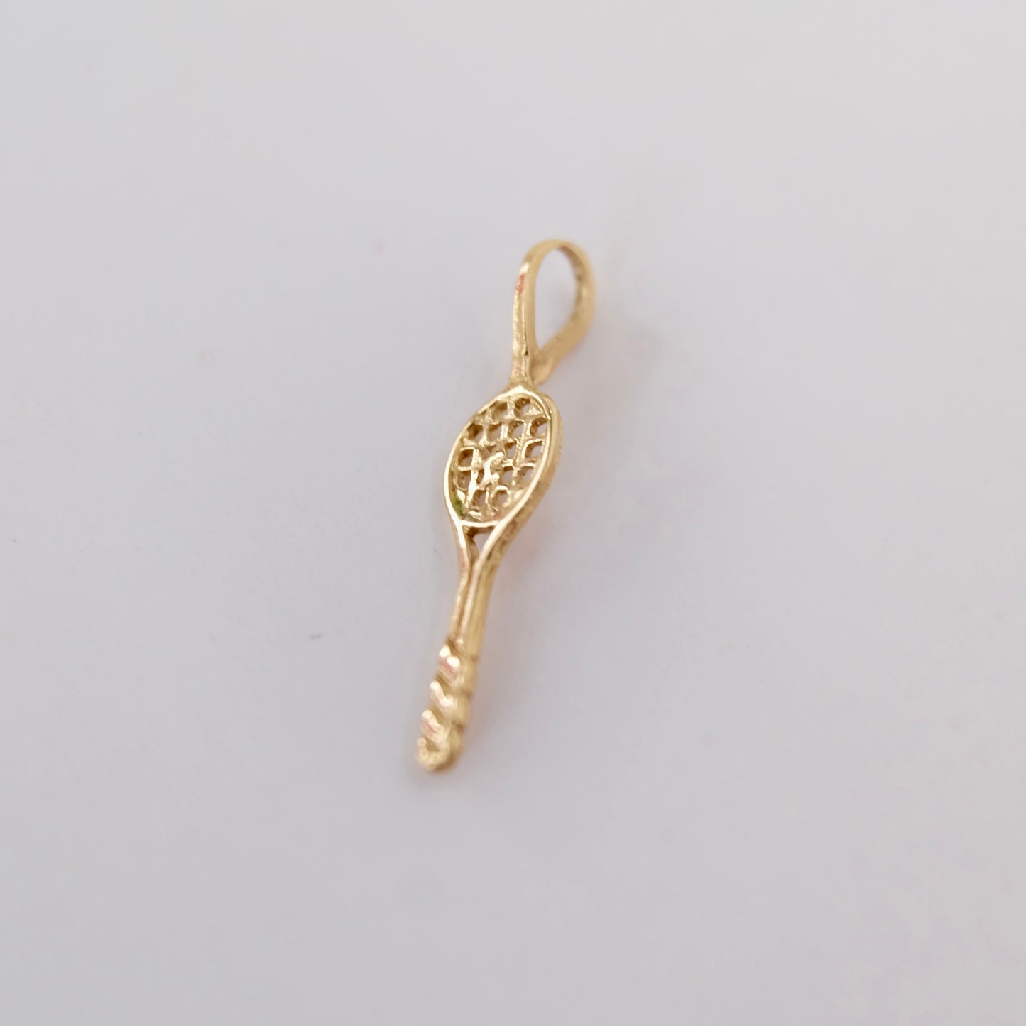 A vintage tennis racquet charm featuring 14k gold displayed on white background. 