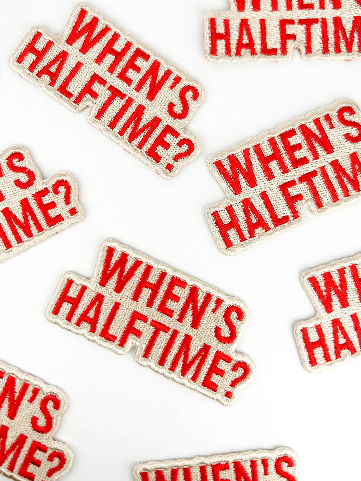 Flat lay of "When's Half Time?" iron-on patches for tailgate gear