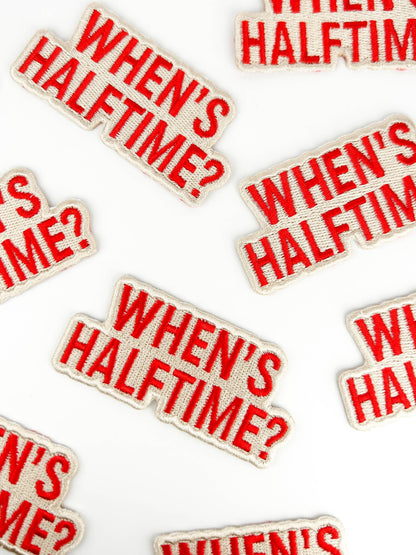 Flat lay of "When's Half Time?" iron-on patches for tailgate gear