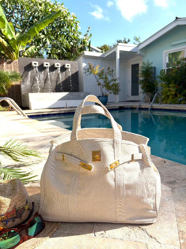 White Boatkin bag open with gold accents by a pool.