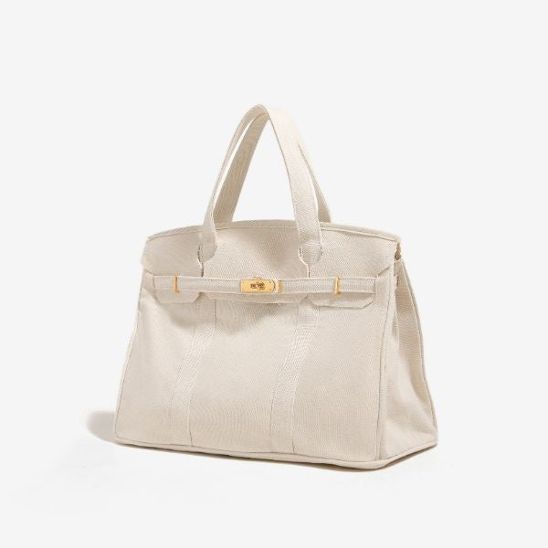 White Boatkin bag side view showing gold hardware and piping.