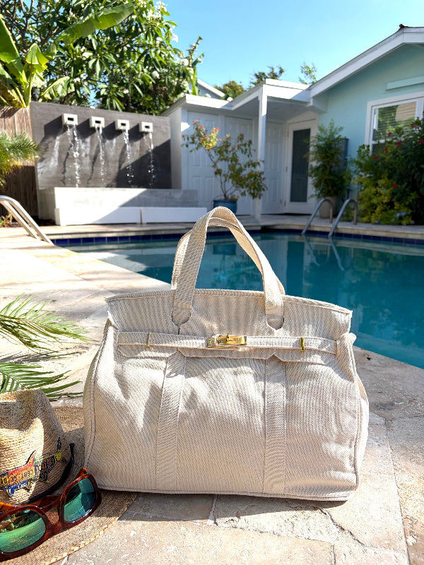 White Boatkin bag by a pool with palm and trees in the background