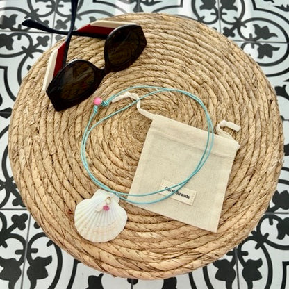 White fan shell mother of pearl pendant with pink topaz on woven mat