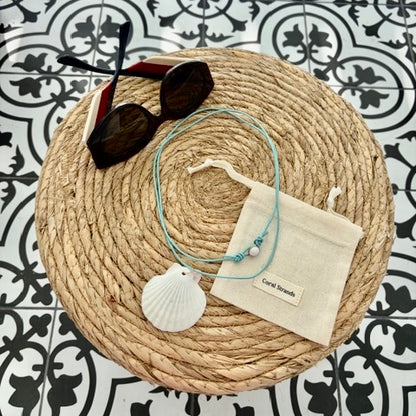 White fan shell necklace with rose quartz on leather cord, styled flat lay